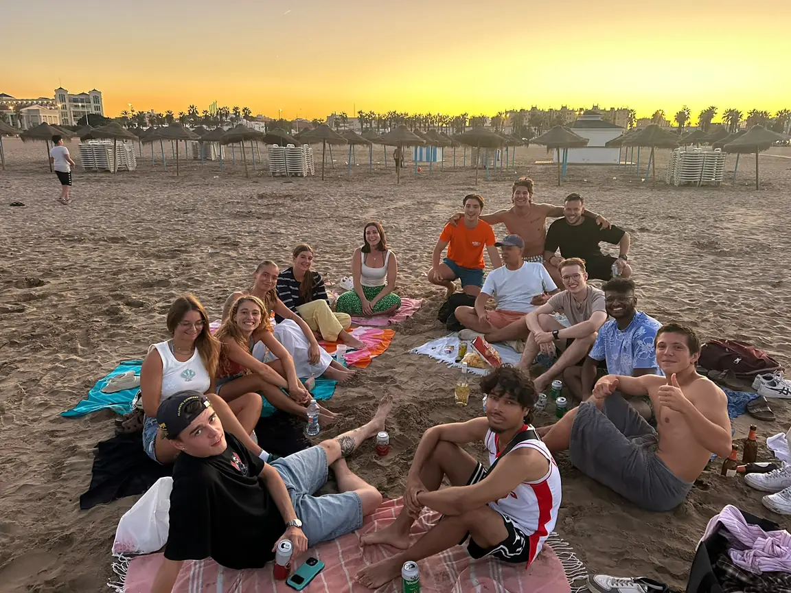 Nexo community members sitting together on Malvarrosa beach in Valencia at sunset